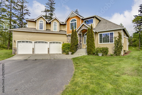 Large home exterior with three car garage spaces. © Javani LLC
