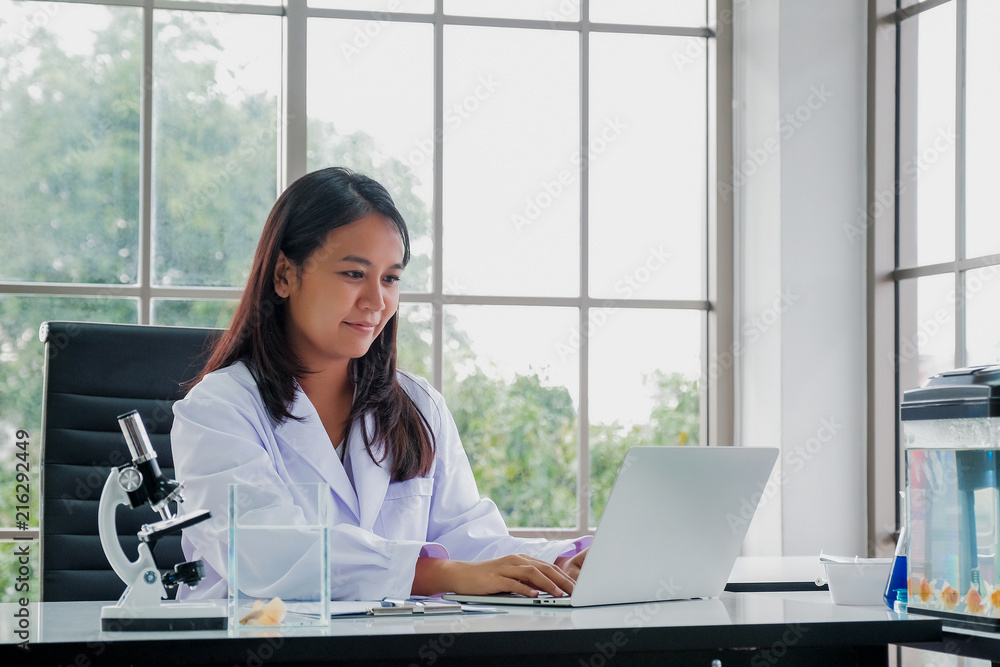 Female Doctor Sitting At Desk Working At Laptop In Office Female Doctor Sitting At Desk Working At Laptop In Office