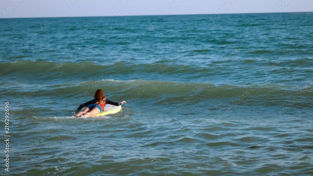 Beautiful slim girl floating on a surfboard in the sea. Professional serfengist at sea Beautiful slim girl floating on a surfboard in the sea. Professional serfengist at sea