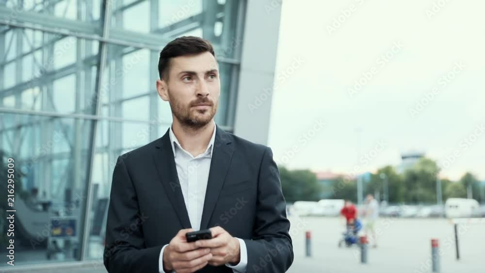 Handsome Businessman Chatting on his Smartphone While Exiting the Big Building. Checking News, Mails.Looking Confident, Successful. Classically Dressed. Walking in the City. Handsome Businessman Chatting on his Smartphone While Exiting the Big Building. Checking News, Mails.Looking Confident, Successful. Classically Dressed. Walking in the City.