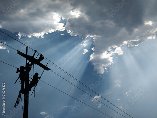 Power lineman maintain high-strength distribution system. The backdrop is a beautiful blue sky.