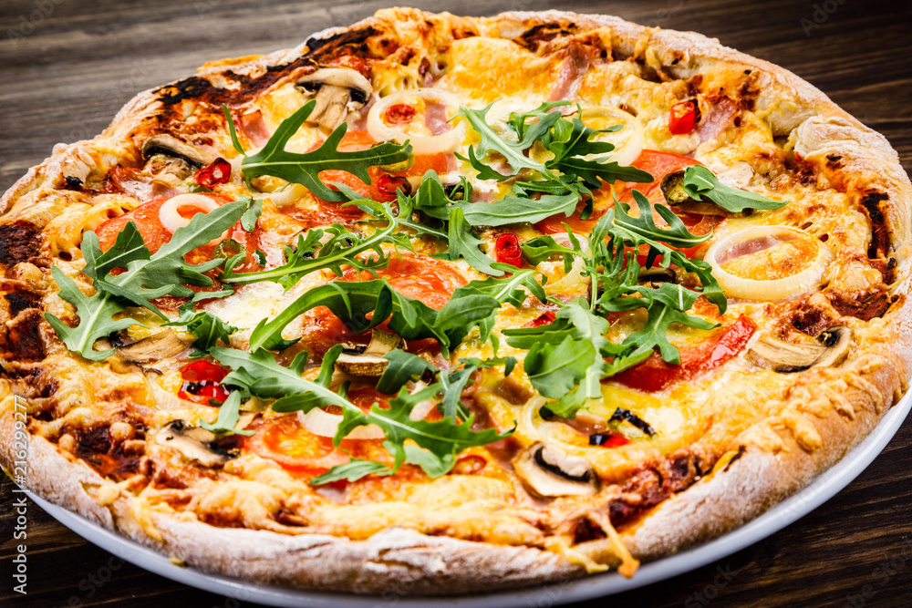 Pizza with ham and vegetables on wooden table Pizza with ham and vegetables on wooden table