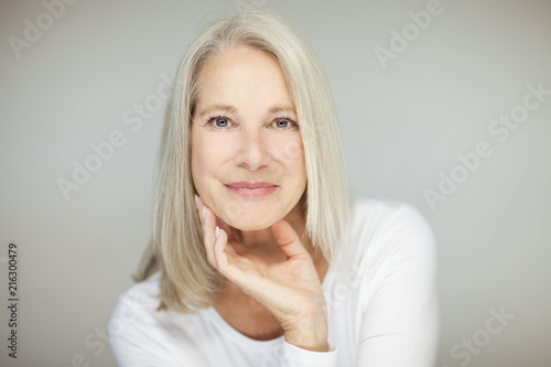 stunning beautiful and self confident best aged woman with grey hair smiling into camera, portrait with white background 