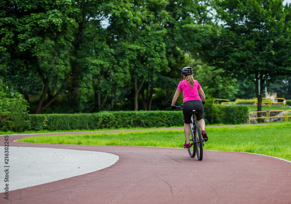 Healthy lifestyle - woman riding bicycle in city park 