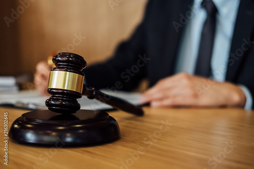 Gavel on wooden table and Lawyer or Judge working with agreement in Courtroom theme, Justice and Law concept