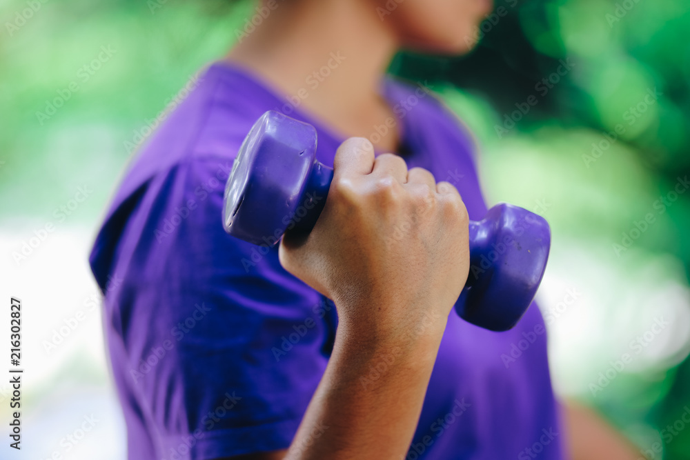 Close Up mid section of a young woman lifting dumbbell weight