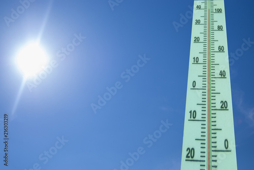 Thermometer with a temperature of +40 degrees Celsius on a background of bright sun and blue sky