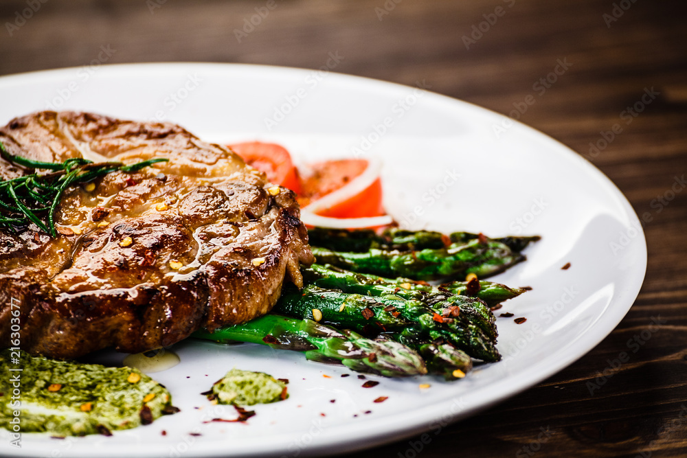 Grilled beefsteak with asparagus on wooden background 