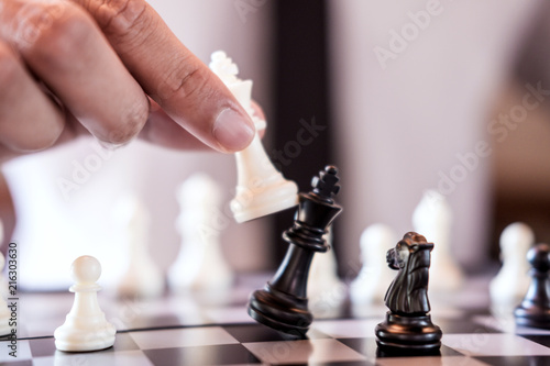 Hand of confident businessman use king chess piece white playing chess game to crash overthrow the opposite team and development analysis new strategy plan, business strategy for win and success