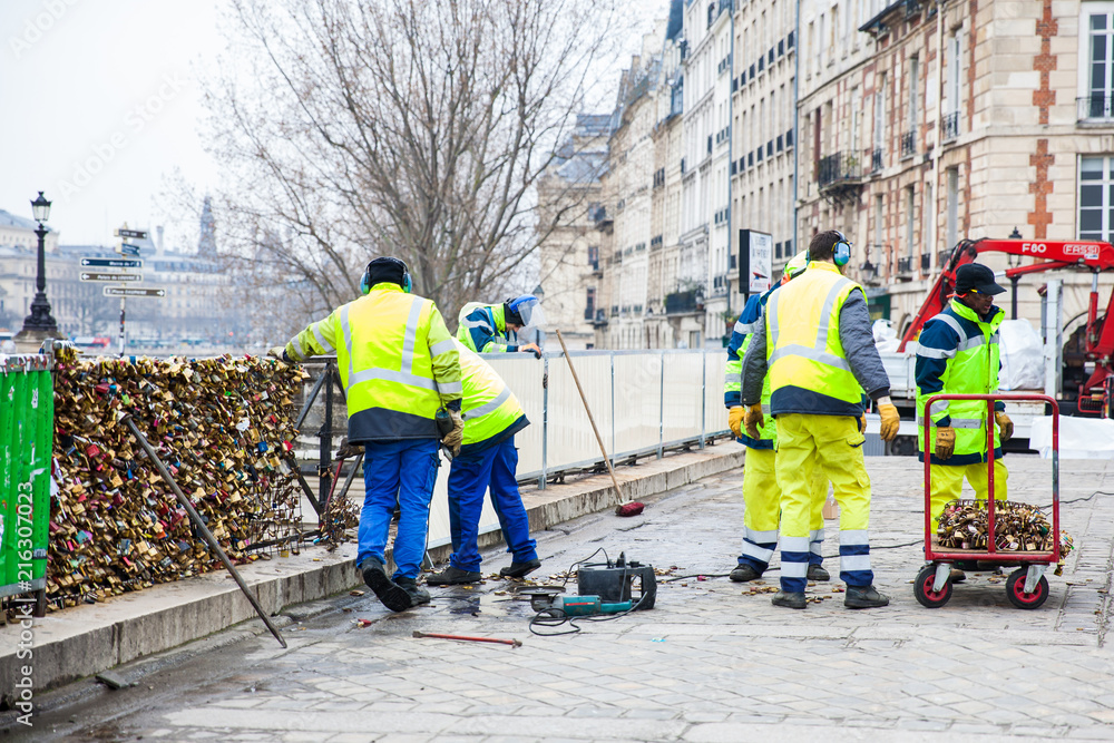 Group of workers removing padlocks at Pont Neuf in Paris