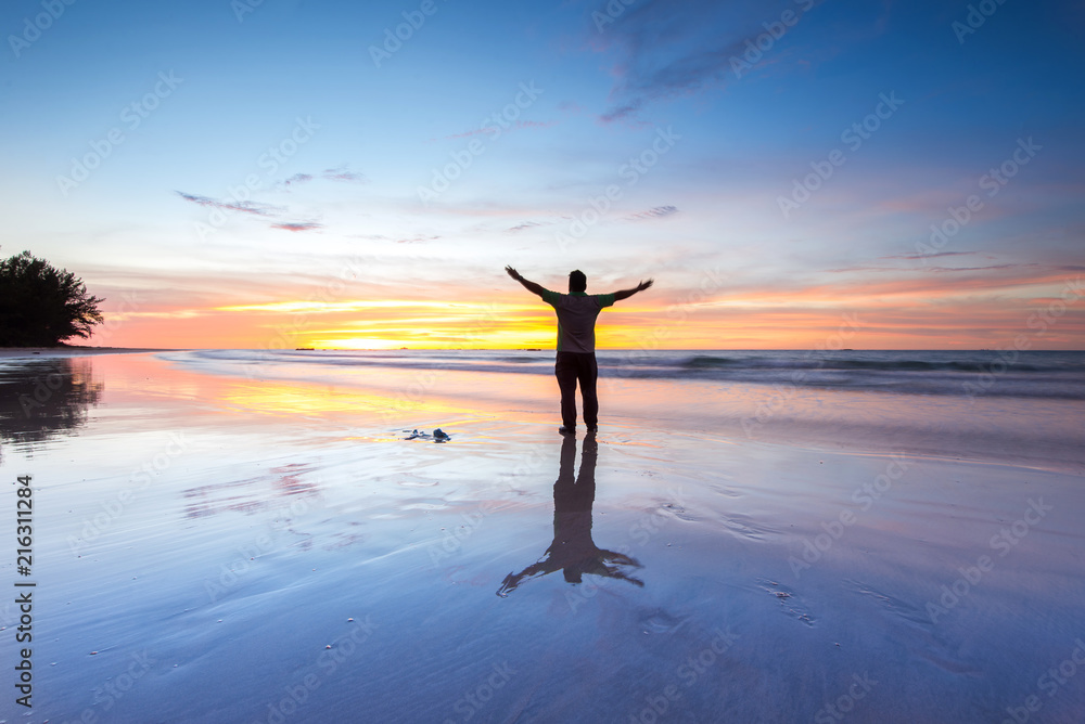 Man at the beach during vibrant sunset. 