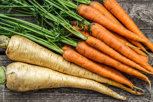 Close up of a bundle of carrots and parsnip on a rustic wooden table. Concept for root vegetable, organic raw food, farming and harvest. photo