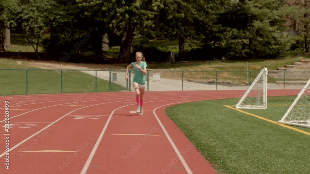 Teen girl runner on a track sprints at and past the camera in Slow Motion. Teen girl runner on a track sprints at and past the camera in Slow Motion.