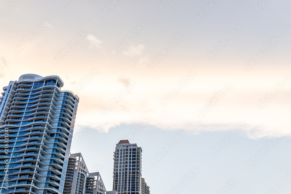Sunny Isles Beach, USA cityscape skyline looking up perspective of apartment condo hotel building balconies during sunset evening in Miami, Florida with skyscrapers urban exterior skyscape