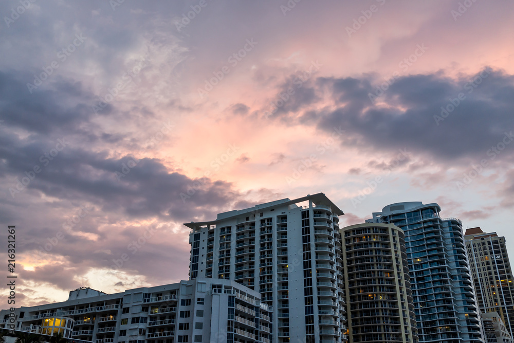 Sunny Isles Beach, USA dramatic cloudscape skyline looking up perspective of apartment hotel buildings during colorful sunset evening in Miami, Florida with skyscrapers urban exterior skyscape