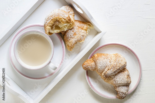 cornetti con  cappuccino o caffe latte  e colazione in vassoio bianco e tazza e piatti bianchi bordati di rosa photo