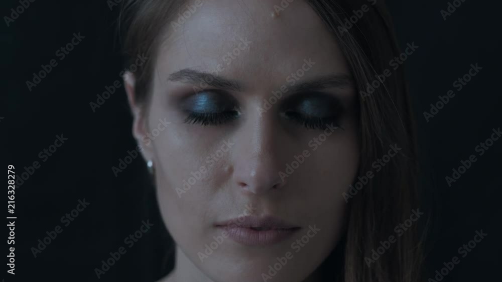 Portrait of a beautiful woman on a black background. Model with bright makeup. Female smiles. Smokey eyes. She opens her eyes.