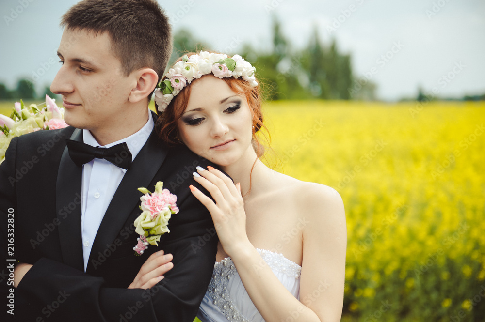 Bride and groom in a blooming yellow field. Wedding day, couple in a rape field. Ukraine Bride and groom in a blooming yellow field. Wedding day, couple in a rape field. Ukraine