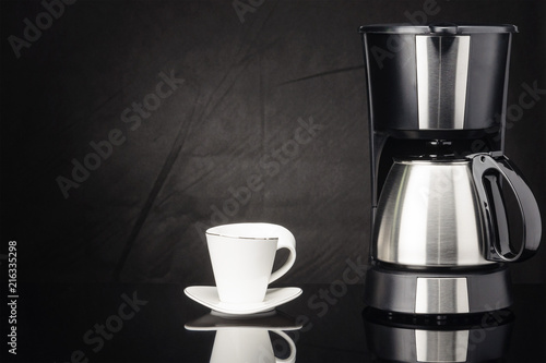 Coffee machine with pot and cup on the black mirror background