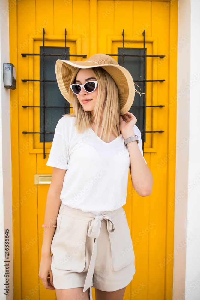 Naklejka premium Outdoor portrait of young beautiful woman wearing trendy clothes posing near the yellow door