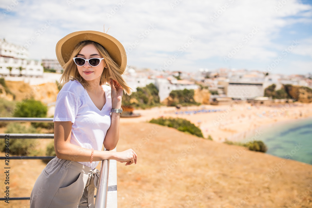 Stylish woman at the summer beach in a hot day in summer hat and sunglasses