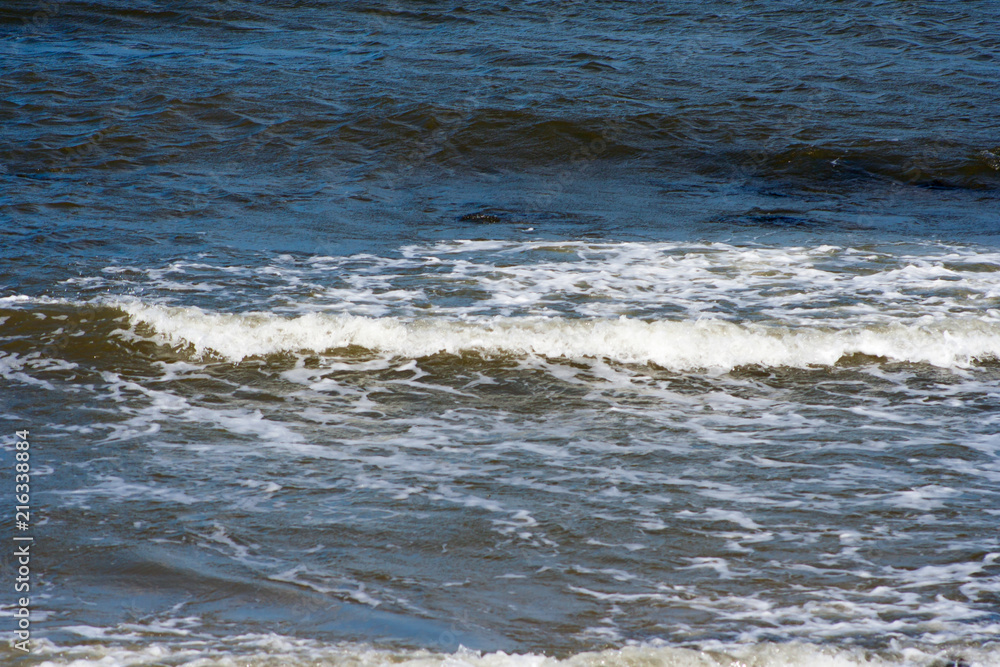 Sea waves crashing against stones lying by the shore. Water and stones on the beach Sea waves crashing against stones lying by the shore. Water and stones on the beach