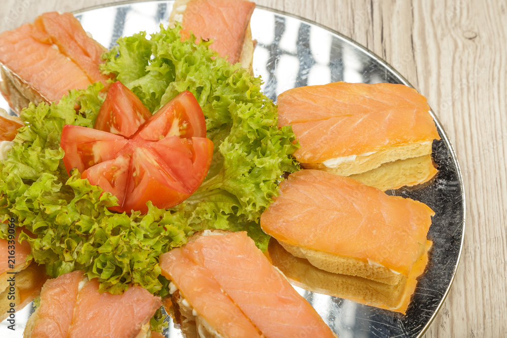Dish of sandwiches with red fish tomato and greens. Dish of sandwiches with red fish tomato and greens.