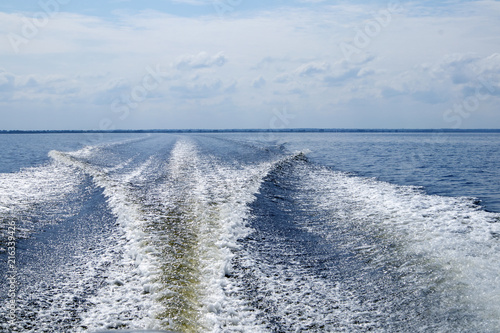 Large boat trail with foamy waves and sprays behind the fast motor boatLarge boat trail with foamy waves and sprays behind the fast motor boat