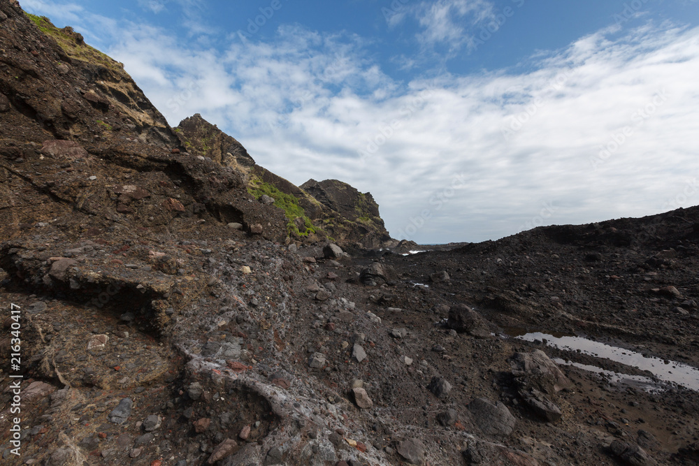 Three Saints Island, Taitung Taiwan, Pacific Coast. Sanxiantai scenic area rock formations, black coral reef formations and blue sky, white clouds in the background.