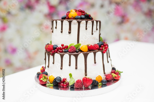 White wedding cake with flowers and leaves on black background isolated. photo