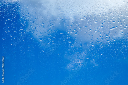 Drops of water on a glass against a cloudy sky background. Seamless texture