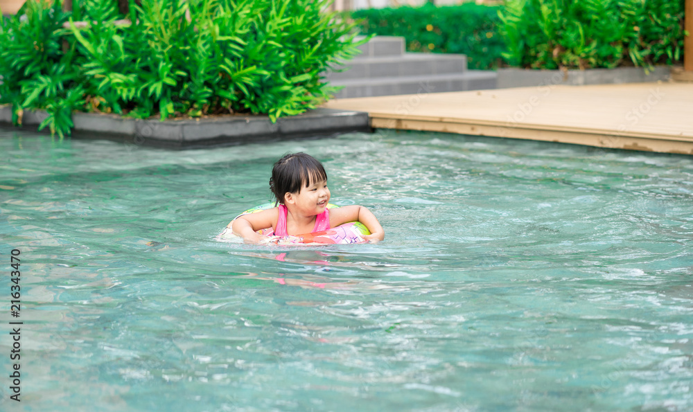 Little girl with rubber ring in swimming pool