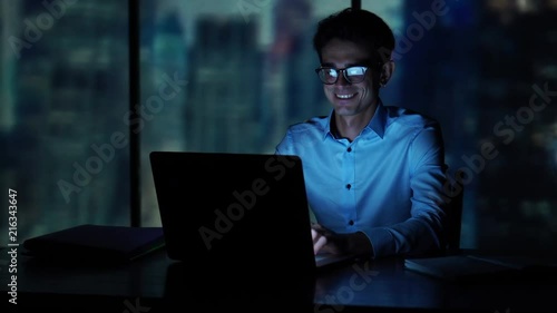 Portrait of young man sitting at his desk in the office. Success and business concept. photo