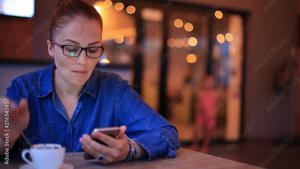 beautiful young woman businessman with red hair and glasses sitting at a table in a cafe and eating dessert. beautiful young woman businessman with red hair and glasses sitting at a table in a cafe and eating dessert.