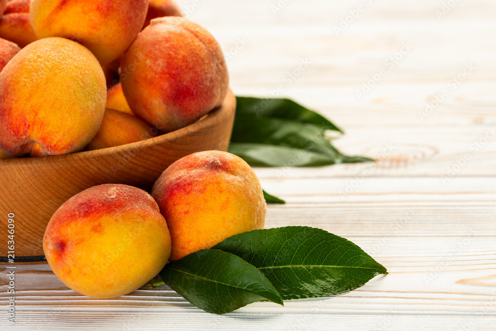 Peaches with leaves close-up on a white wooden table Peaches with leaves close-up on a white wooden table