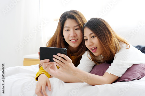Young cute asia lesbian couple using smart phone with happiness at home, lgbt, homosexual, lesbian couple lifestyle