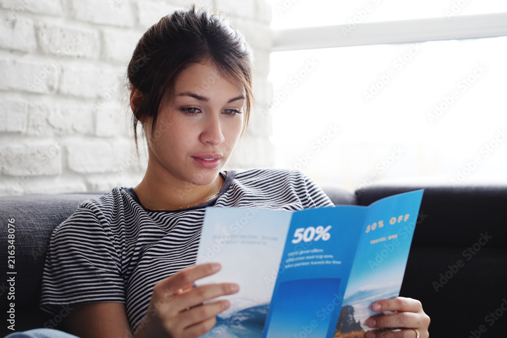 Woman Reading Travel Flye On Sofa At Home - obrazy, fototapety, plakaty 
