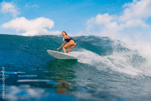 Beautiful surfer woman at surfboard on ocean wave.