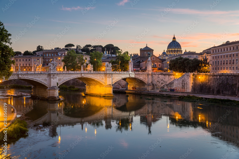 View of St Peter's Cathedral and the Tiber river from Pont Sant'Angelo at dusk