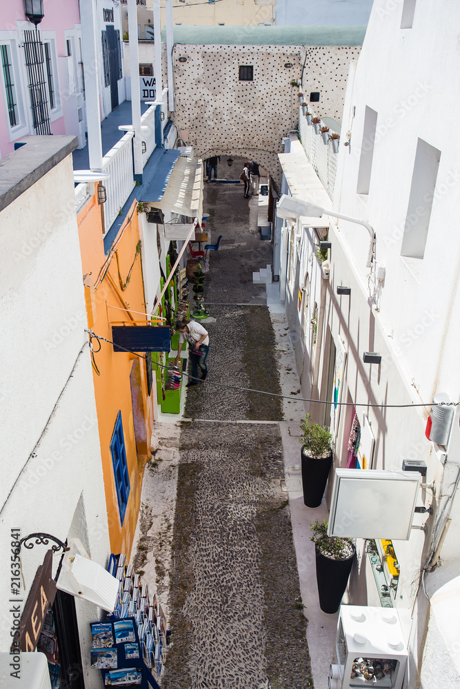 Obraz premium Gourgeous view os street in white walled town of Fira in Santorini, Greece, with shops on either side.