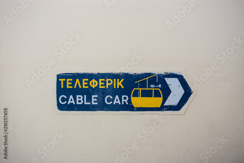 Blue and yellow sign for cable car in Santorini, Greece