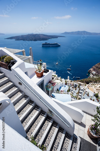 Gourgeous view of stairs in white walled town of Fira in Santorini, Greece, with ocean, cliffs and caldera of Santorini in the background.