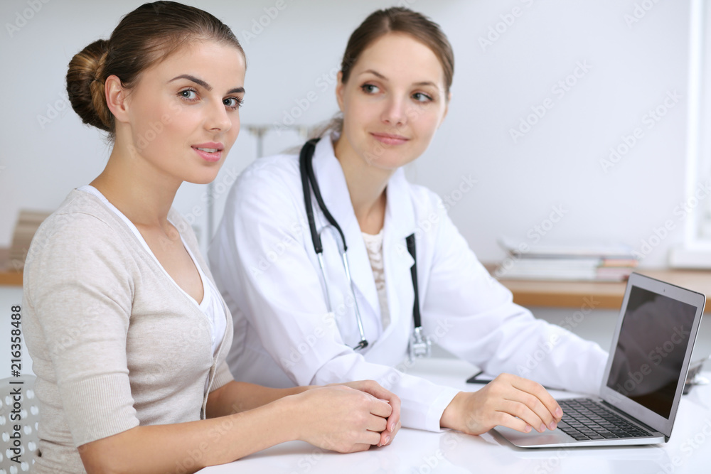 Doctor and patient having a pleasure talk while sitting at the desk at hospital office. Healthcare and medicine concept Doctor and patient having a pleasure talk while sitting at the desk at hospital office. Healthcare and medicine concept