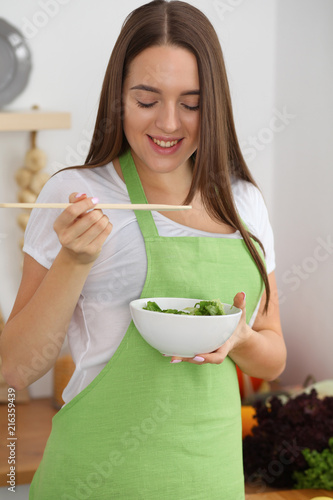 Young woman cooking in kitchen. Householding, tasty food and vegetarian in lifestyle concepts photo