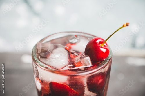 Cold cherry cocktail with ice and strong alcohol. Selective focus.