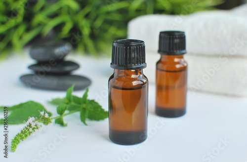 peppermint essential oil in brown bottles, spa stones and white towels.