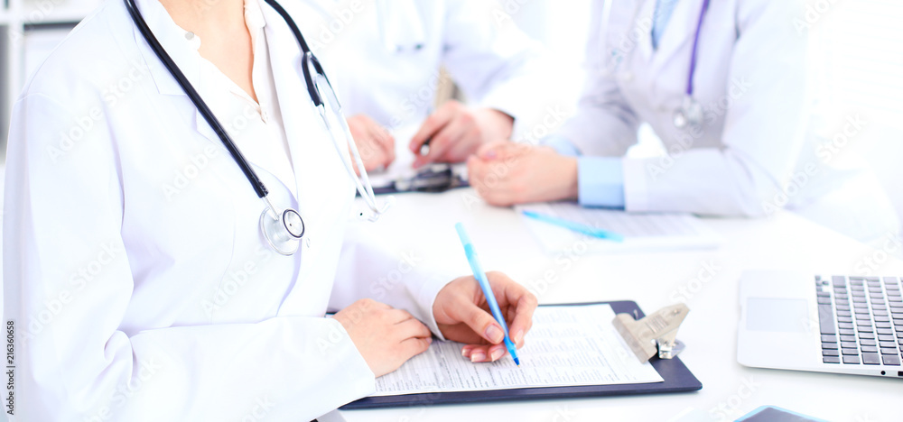 Group of unknown doctors working at hospital while sitting at the table. Teamwork and success concept in medicine Group of unknown doctors working at hospital while sitting at the table. Teamwork and success concept in medicine