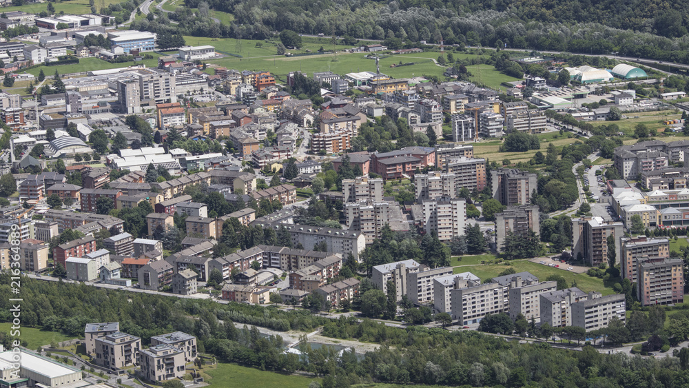 A green small city situated inside alps full of green grass and trees