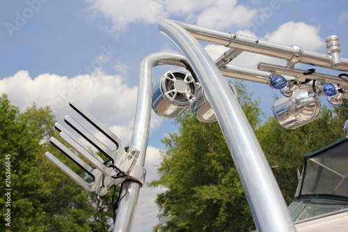 Close up tower, Targa top, a pole for towing water-skiing on a motor boat with speakers and a mount for wake riding in summer day against green trees and blue sky photo