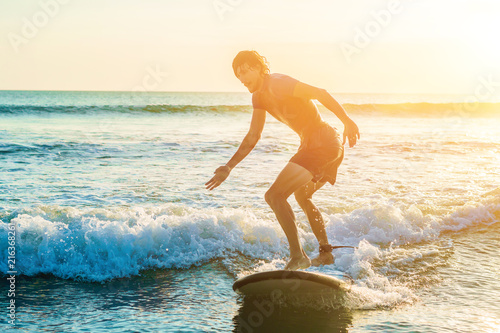 Obraz na plátně Young man, beginner Surfer learns to surf on a sea foam on the Bali island
